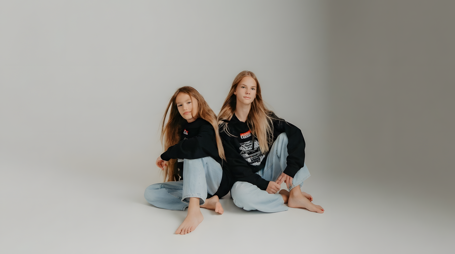 Forever Classic kids’ rally clothing collection with two girls wearing black hoodies and car graphic T-shirts