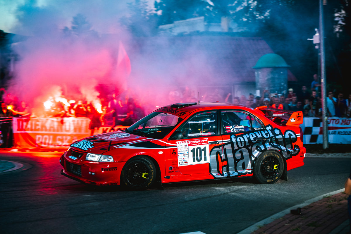 Forever Classic rally car at night surrounded by fans with flares and smoke